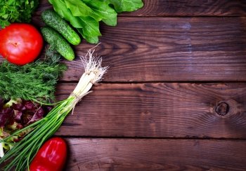 Fresh vegetables and parsley with dill on a brown wooden background, empty space on the right