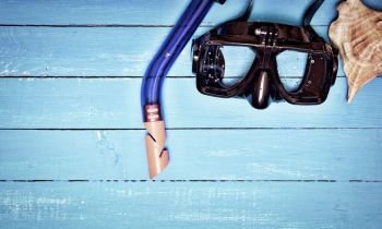 scuba mask and snorkel on a blue wooden background, empty space