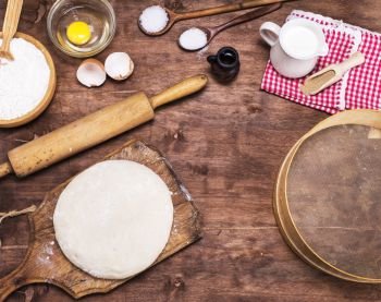 yeast dough made from white wheat flour and ingredients on a brown wooden table, top view