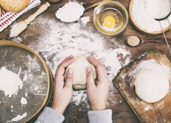 women’s hands hold a ball of yeast dough on a table in the middle of the ingredients for bread making, vintage toning