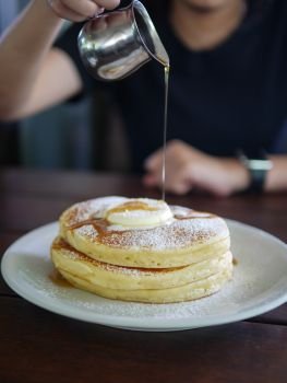 Stack of pancakes with butter on top dressing with maple syrup