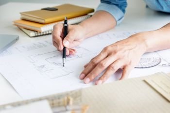 Person’s engineer Hand Drawing Plan On Blue Print or working project in his office with architect equipment