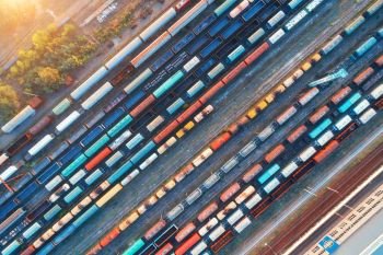 Top view of colorful cargo trains. Aerial view from flying drone of colorful freight trains on the railway station. Wagons with goods on railroad. Heavy industry. Industrial conceptual scene. Vintage