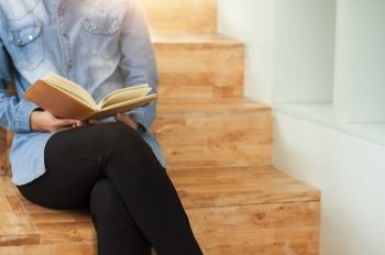 Beautiful student woman sitting at the stair and reading a book