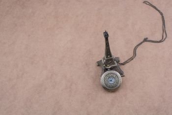 Little model Eiffel Tower  and a pocket watch on brown background