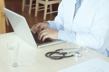 Professional medical doctor in white uniform gown coat working laptop computer