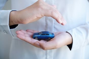 Concept of car insurance with Protection of a car. toy car and hand Business concept. 