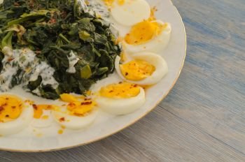 traditional and regional food. spinach is served with roasted garlic yogurt and boiled eggs.There is red pepper on it.