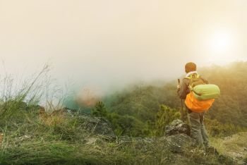 Traveler with backpack trekking on top of mountain in morning with fog while sunrise. Feeling freedom with beautiful natural. Travel and vacation concept.