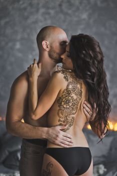 Passionate kiss of a man and a girl with a tattoo.. The pattern of the mehendi on your naked back girls 217.
