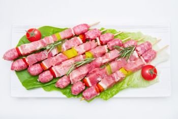 group of meat skewers on dish on white background