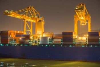 Cranes, ship and containers in a commercial port at night