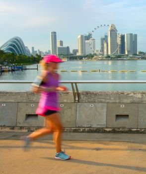 Woman jogging at sunset in Singapore bay. Motion blur