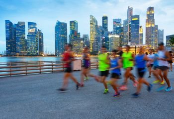 Group of runners on Singapore quayside at twilight, Singapore Downtown on a background