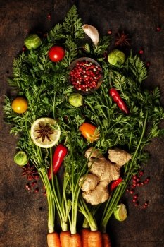 fresh carrots bunch, herbs and spices on dark rustic background