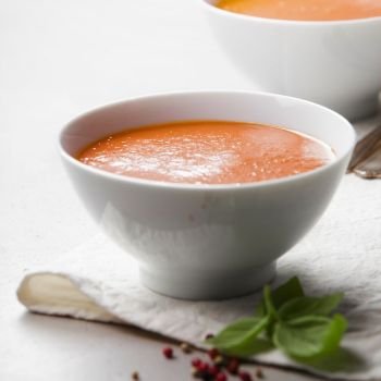 Homemade tomato cream soup in bowls  (or gazpacho) over concrete background