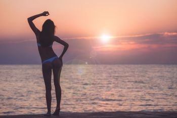 Beautiful woman silhouette over ocean sunrise background