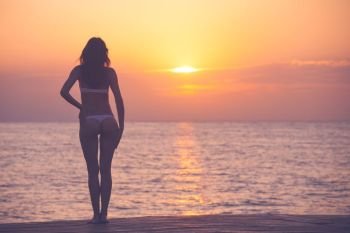 Woman silhouette over ocean sunrise background