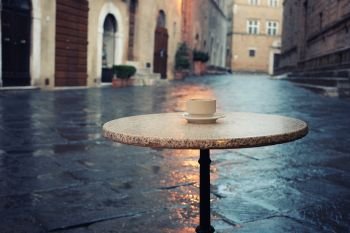Cup of coffee on the old european city street cafe table