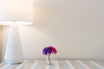 Beautiful flowers with table lamp over white wall background