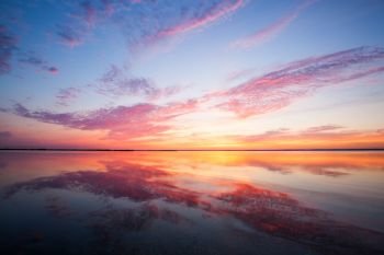 Cloudy sunset over sea. Cloudy colorful sunset over calm sea water surface