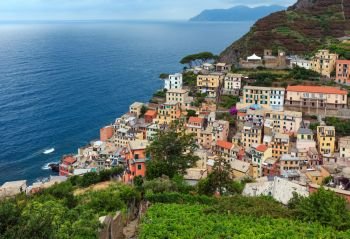 Beautiful summer Riomaggiore - one of five famous villages of Cinque Terre National Park in Liguria, Italy, suspended between Ligurian sea and land on sheer cliffs. People unrecognizable.