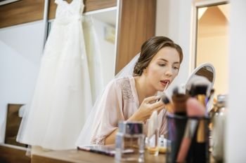 Makeup applying lipstick on bridea€™s lips with brush. Focus on her lips!