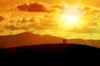 An image of a couple and the dog out for a walk at the sunset
