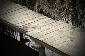 abstract view of a wooden footbridge on small pond