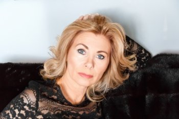 Horizontal portrait of adult blond woman with makeup on black fur