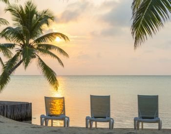 Sunrise On Dream Beach Vacation. Sunrise over the ocean on dream beach vacation with palmtrees and deckchairs