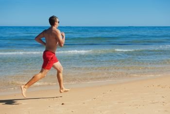 muscular young man running along the coast