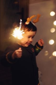Little happy kid holding a sparkling stick and dancing with joy