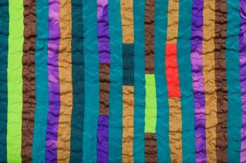 textile background - stitched patchwork scarf from many vertical narrow silk strips