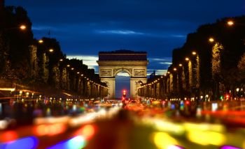 Evening rush-hour on Champs Elysee with the view of illuminated Arc de Triomphe in Paris, France