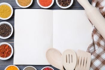 Various spices selection and notepad for copy space on wooden table