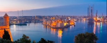 Grand harbor and Senglea from Valletta, Malta. Panoramic aerial skyline view of ancient defences of Three cities, three fortified cities of Birgu, Senglea and Cospicua and Grand Harbor with ships, as seen from Valletta during morning blue hour, Malta.