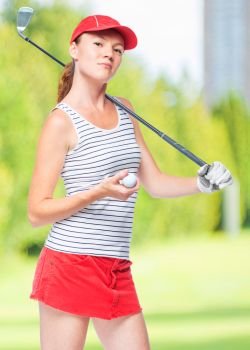 Slender sportswoman golfer with stick and ball on a background of golf courses