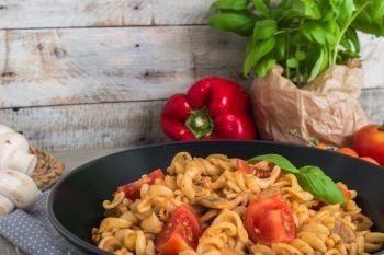 Italian wholemeal pasta with tuna, mushrooms and basil. Fresh pasta with tuna and tomato sauce on old wooden background. Italian cuisine concept.