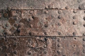 Rusty metal texture. Studded iron plate. Rivets on old rusty metal door. Weathered aged grunge texture.