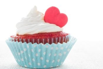 Red velvet heart cupcake with cream cheese frosting and a red heart for Valentine’s Day. White background with copy space