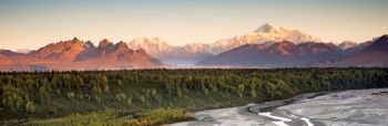 The sun finally meets the horizon hitting Mount McKinley and the Denali range on a long summer day in Alaska