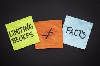 limiting beliefs are not facts concept - handwriting on sticky notes against black paper background