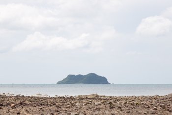 Island and sandy beaches. Large island in the middle of the sea. In front of a beach with small stones.
