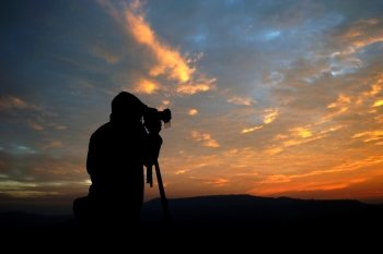silhouette of a photographer taking pictures of the beautiful sunrise