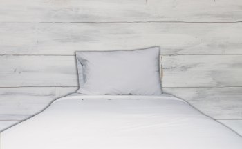 Close up white bedding sheet and pillow with white wooden wall texture background