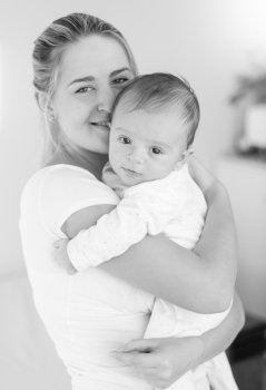 Black and white image of cheerful young mother hugging her baby boy