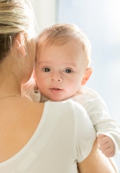 Closeup portrait of 3 months old baby boy hugging mother