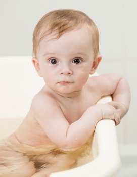 Closeup portrait of cute baby boy bathing and looking at camera