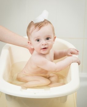 Portrait of adorable baby boy with foam on head having bath time